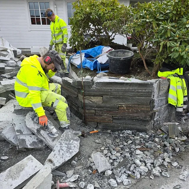 Arbeidere opparbeider steinmur i innkjøring til bolighus