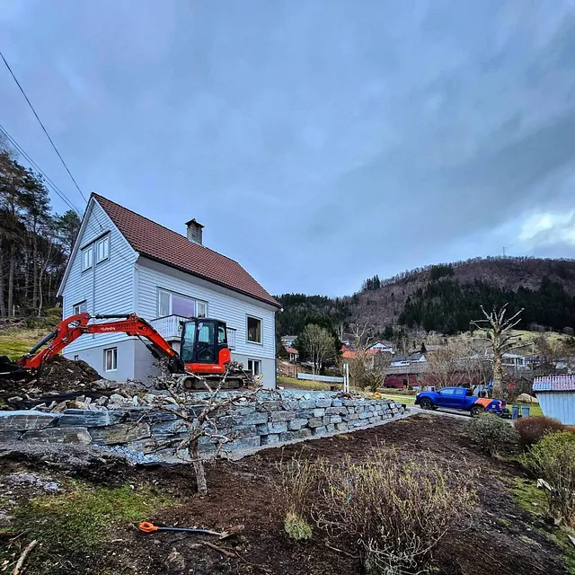 Gravemaskin foran hvitt bolighus